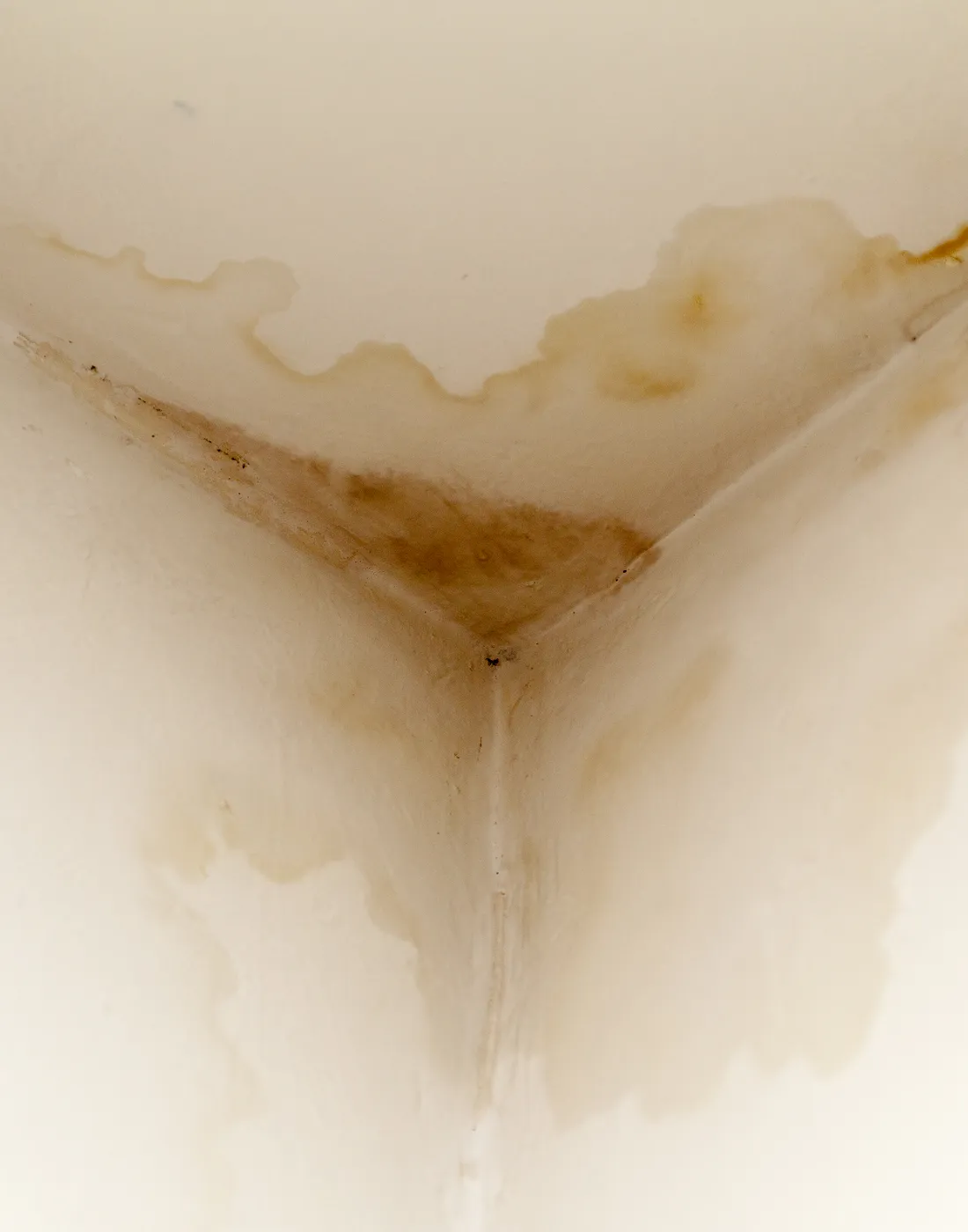 Water staining spreading across a ceiling corner